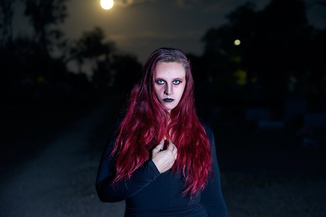 Starrgazzee standing outdoors at dusk with red hair over a black outfit