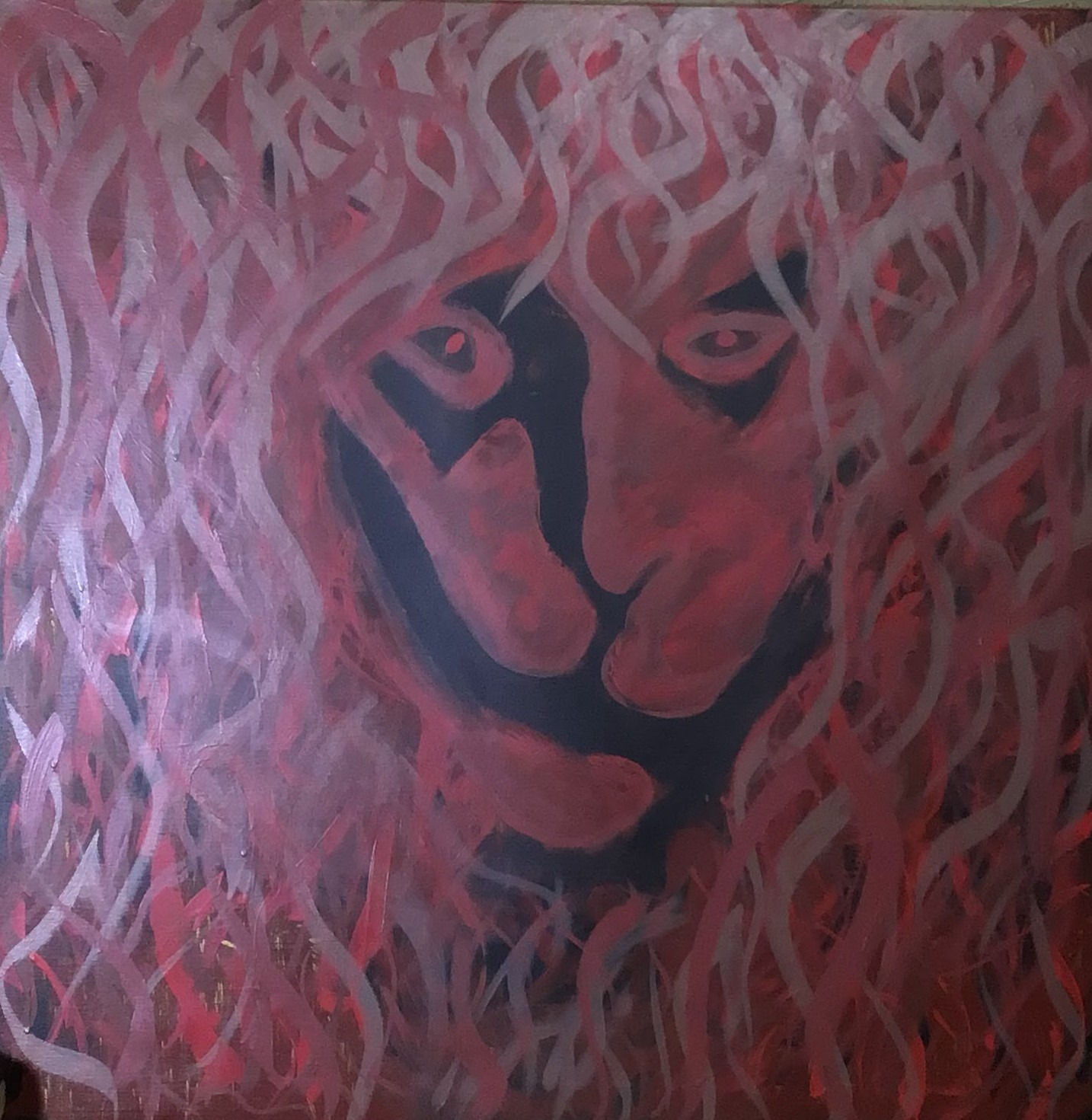 A lion face in black, red and pink beneath a flowing painted mane