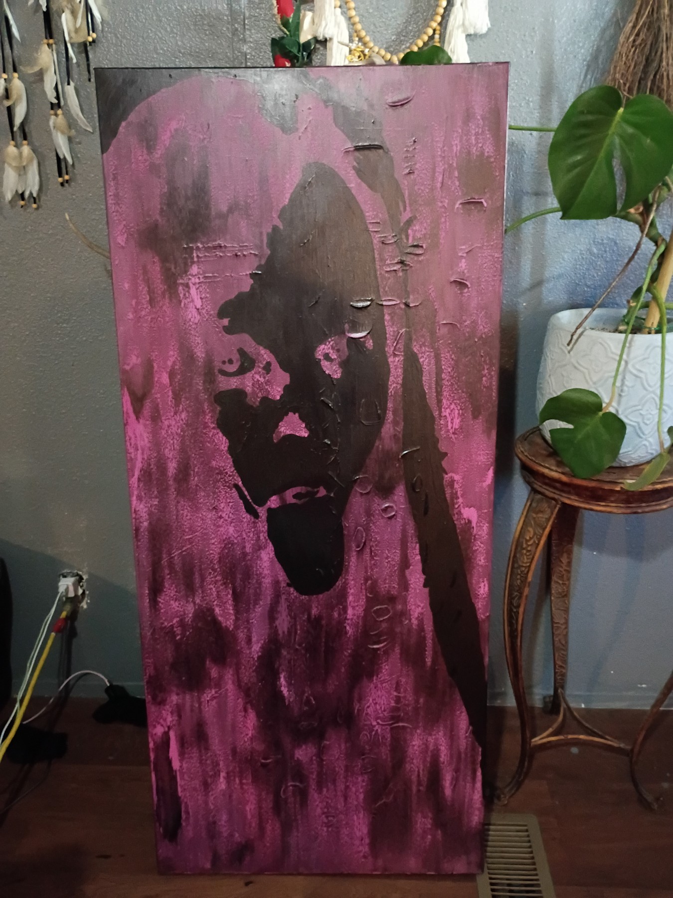 Tall textured black and pink face painting. Shown in a room.