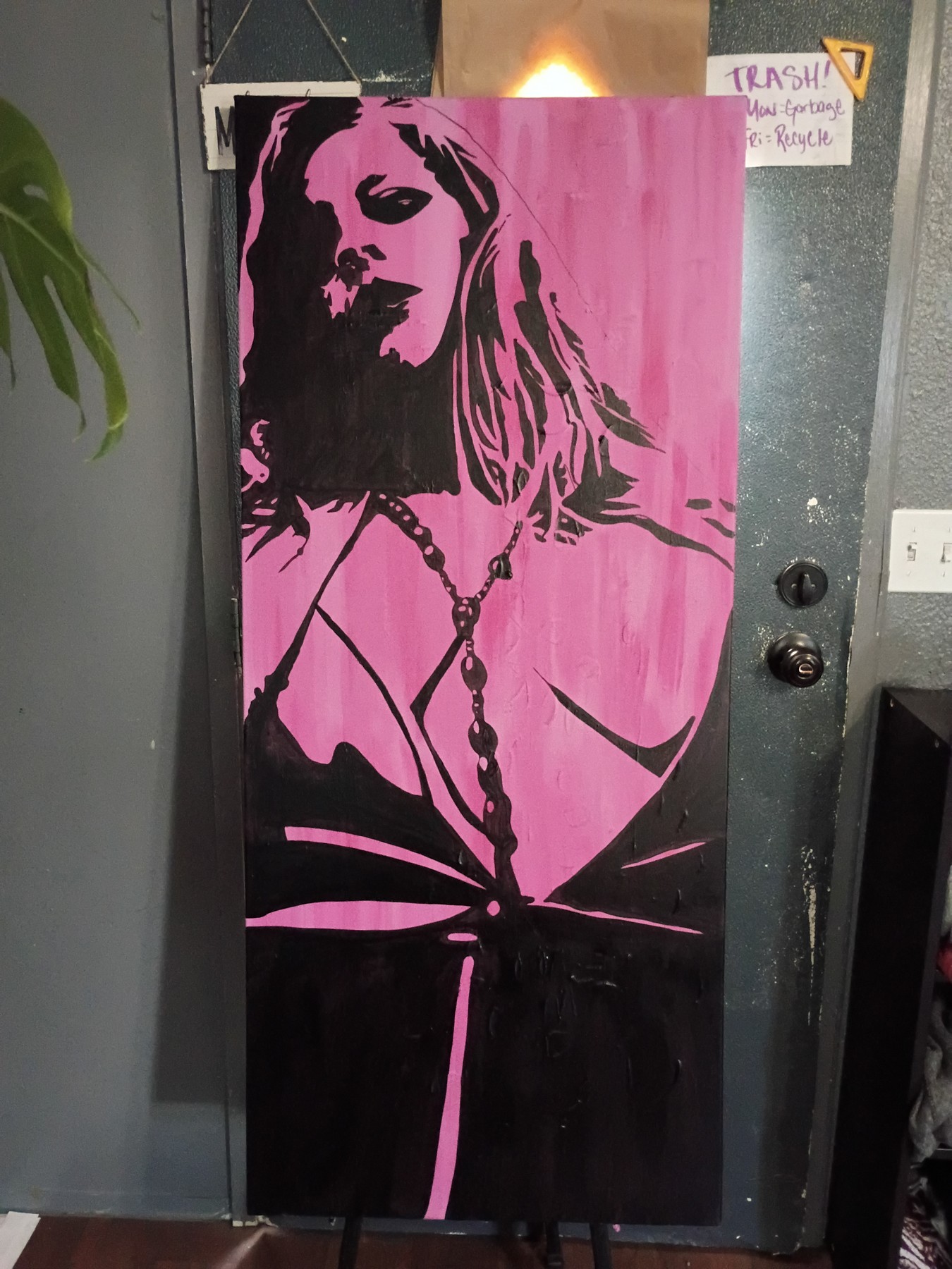 Tall black and pink portrait of a woman wearing necklaces and a strappy top. Shown in a room.