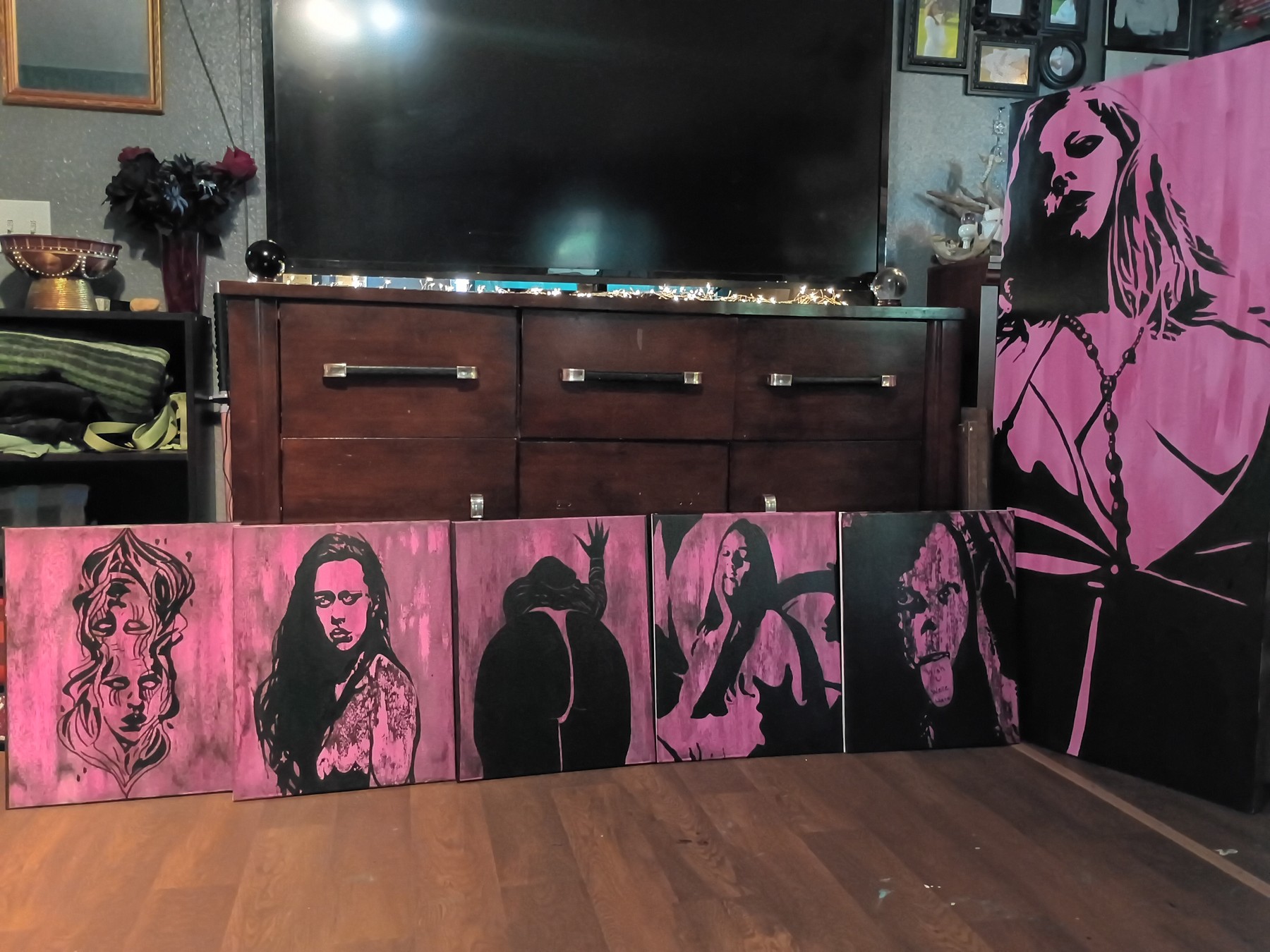 Two opposing faces painted in black on a pink canvas. Shown in a room.