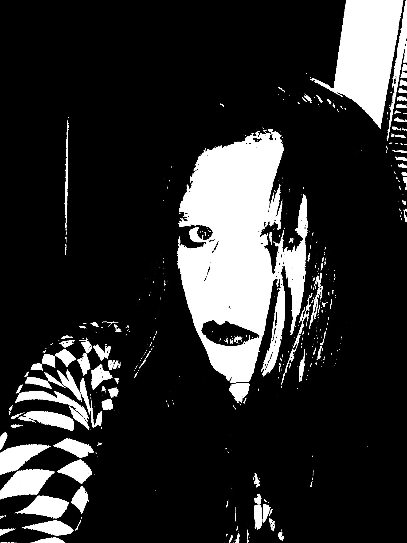 Close portrait framed by deep black shadow and a checkered sleeve