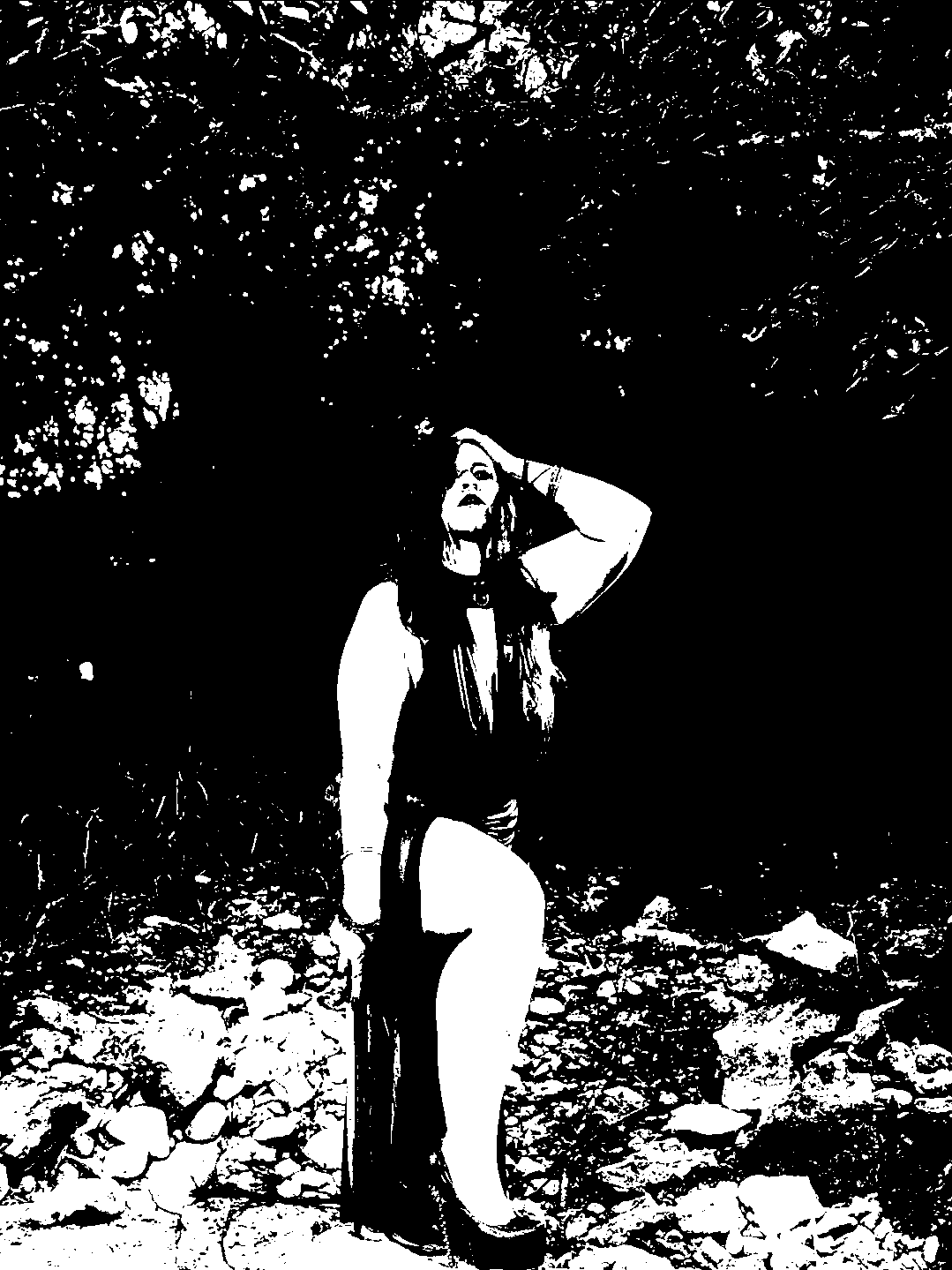 Figure seated outdoors with one hand raised to the head